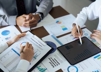 Business people teamwork with analysis cost graph on desk at meeting room Business people teamwork with analysis cost graph on desk at meeting room.